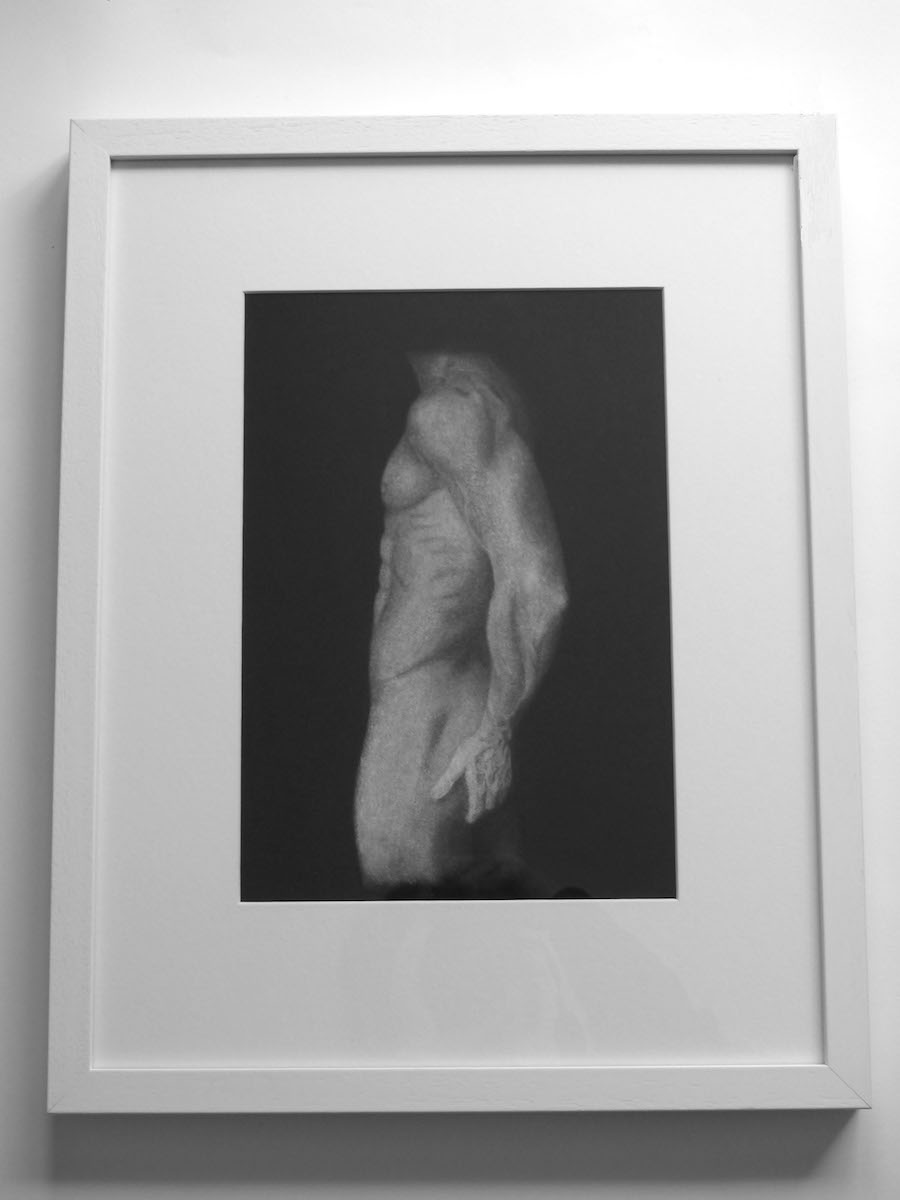 Chalk drawing of man's body on black paper framed