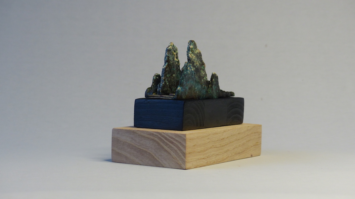 Green patinated brass mountain and fisherman ring sculpture side back angle