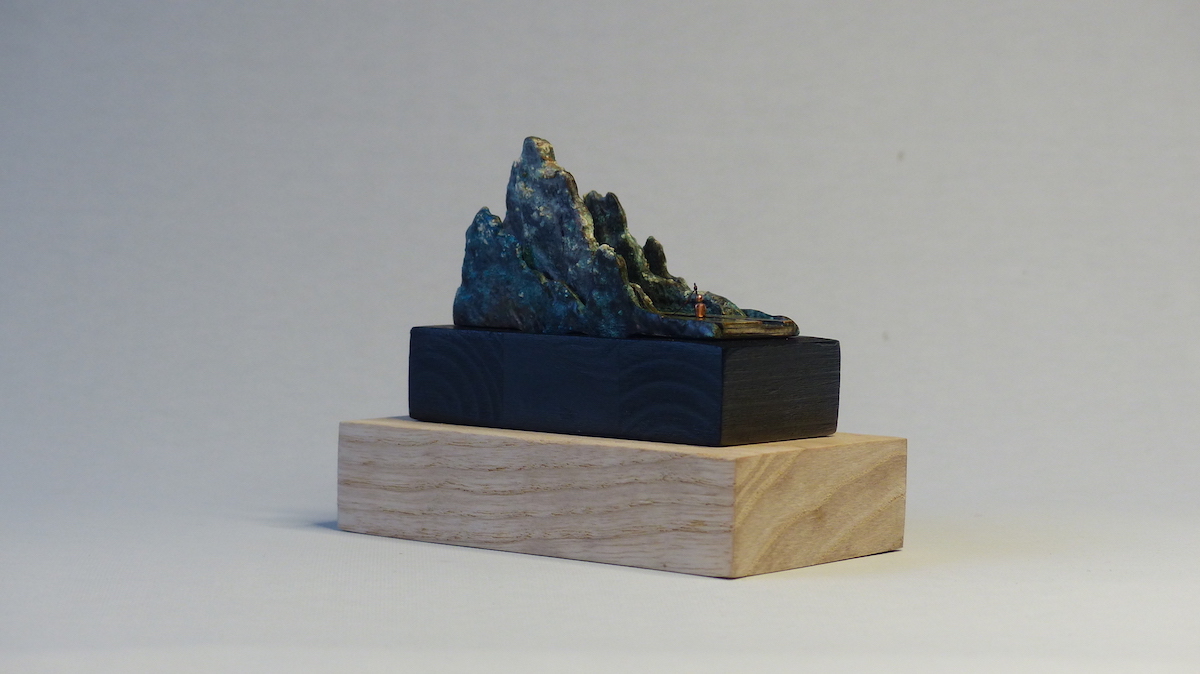 Green patinated brass mountain and fisherman ring sculpture side back angle